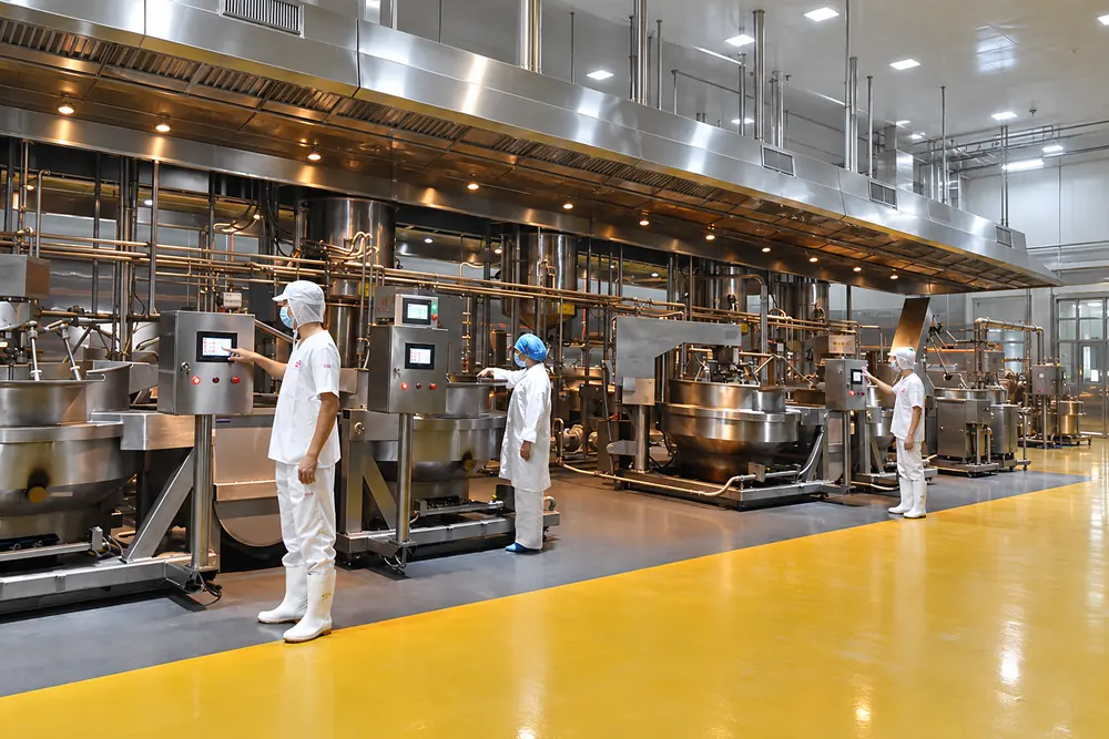 Xưởng nồi xào cốt tự động, công nhân mặc đồ bảo hộ trắng